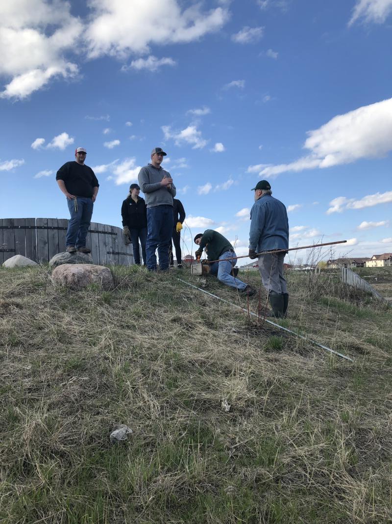 students using tools on a grassy hill